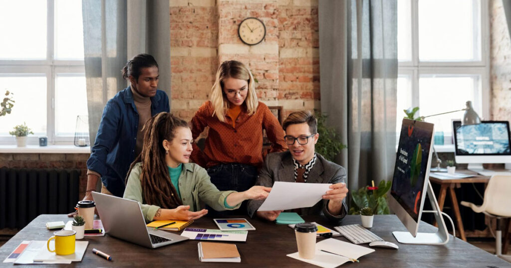 A diverse team of professionals collaborating in a modern office, reviewing marketing strategies and branding materials