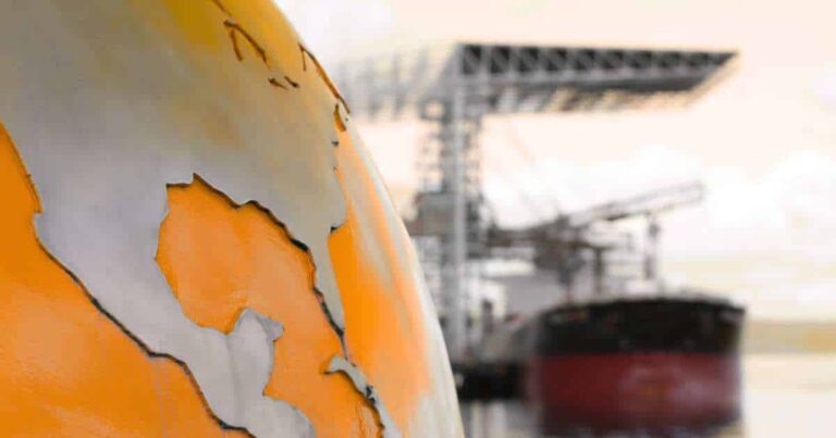 A close-up shot of a globe with a cracked and peeling surface, symbolizing a fragile global economy, with a blurry cargo ship in the background.